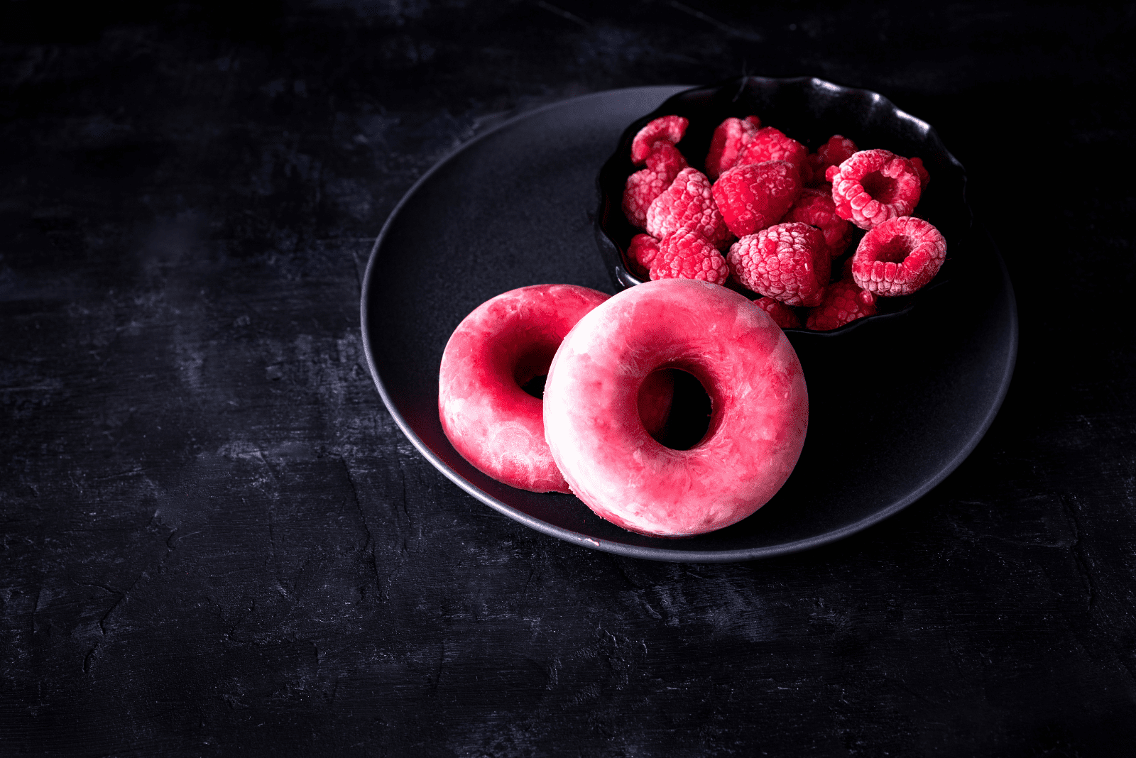 raspberry donuts on a black plate