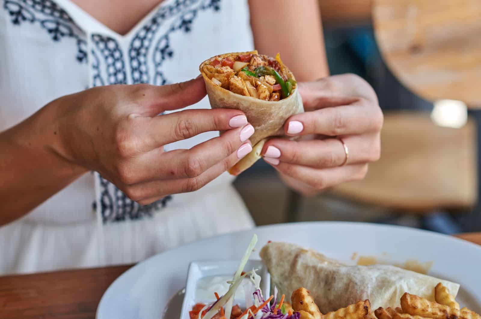 Female hands holding tasty mexican burrito 