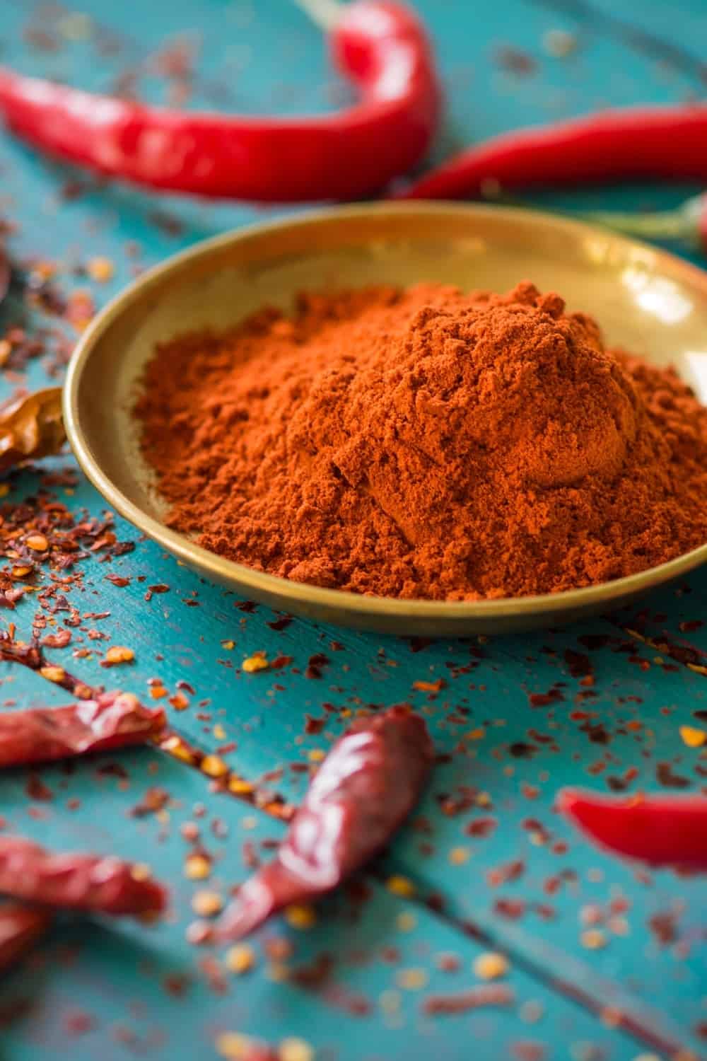 Chili powder and fresh and dried peppers on table background