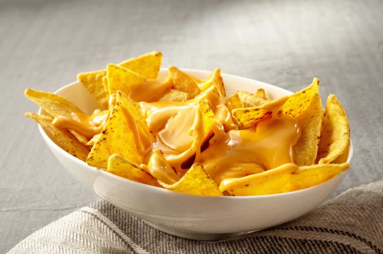 bowl of yellow tortilla chips topped with melted cheese 