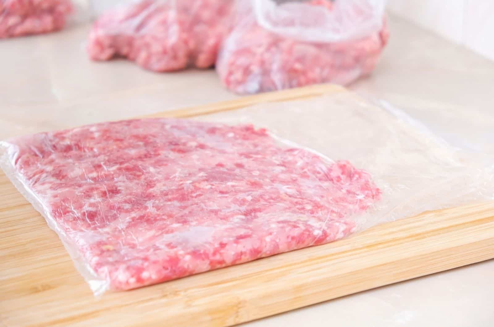 Ein Mann macht flaches Hackfleisch aus Schweine- und Rindfleisch in Beuteln für die Lagerung im Gefrierschrank