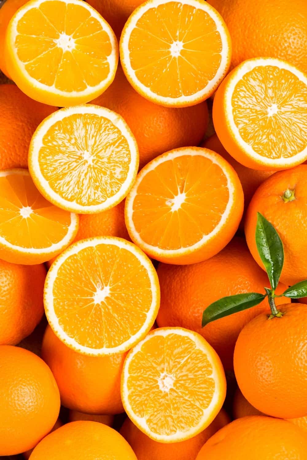 Arrière-plan de fruits entiers et de moitiés d'oranges fraîches et sucrées avec des feuilles vertes