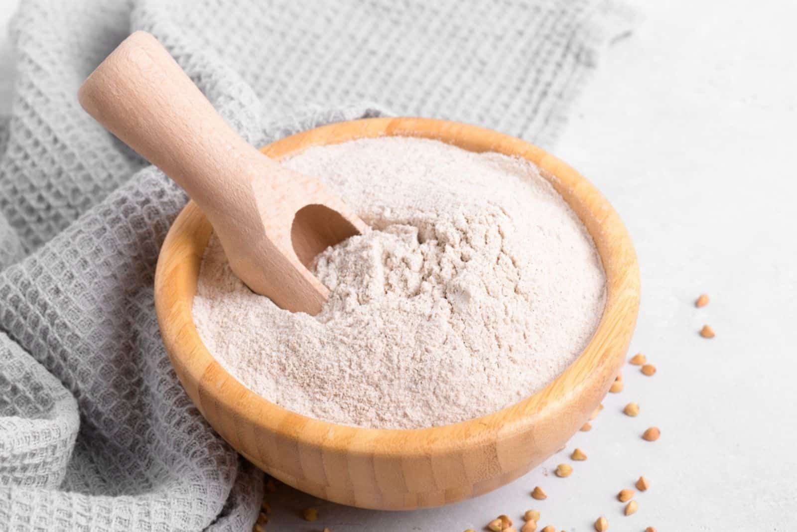 Buckwheat flour in a wooden bowl with wooden scoop