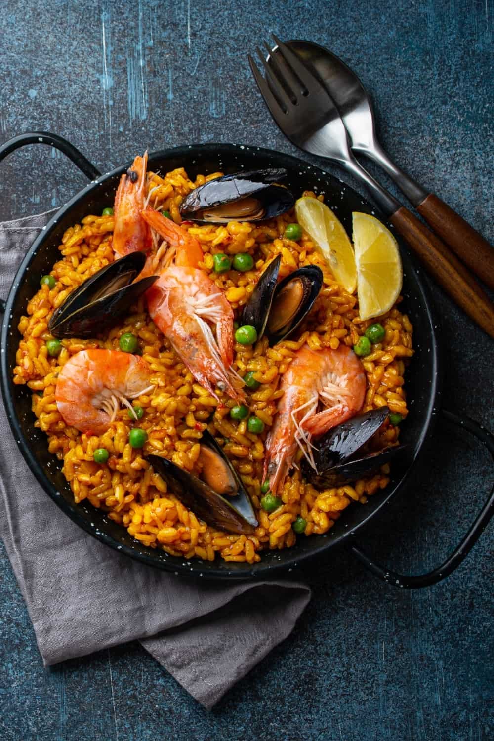 Classic dish of Spain, seafood paella in traditional pan on blue stone background top view