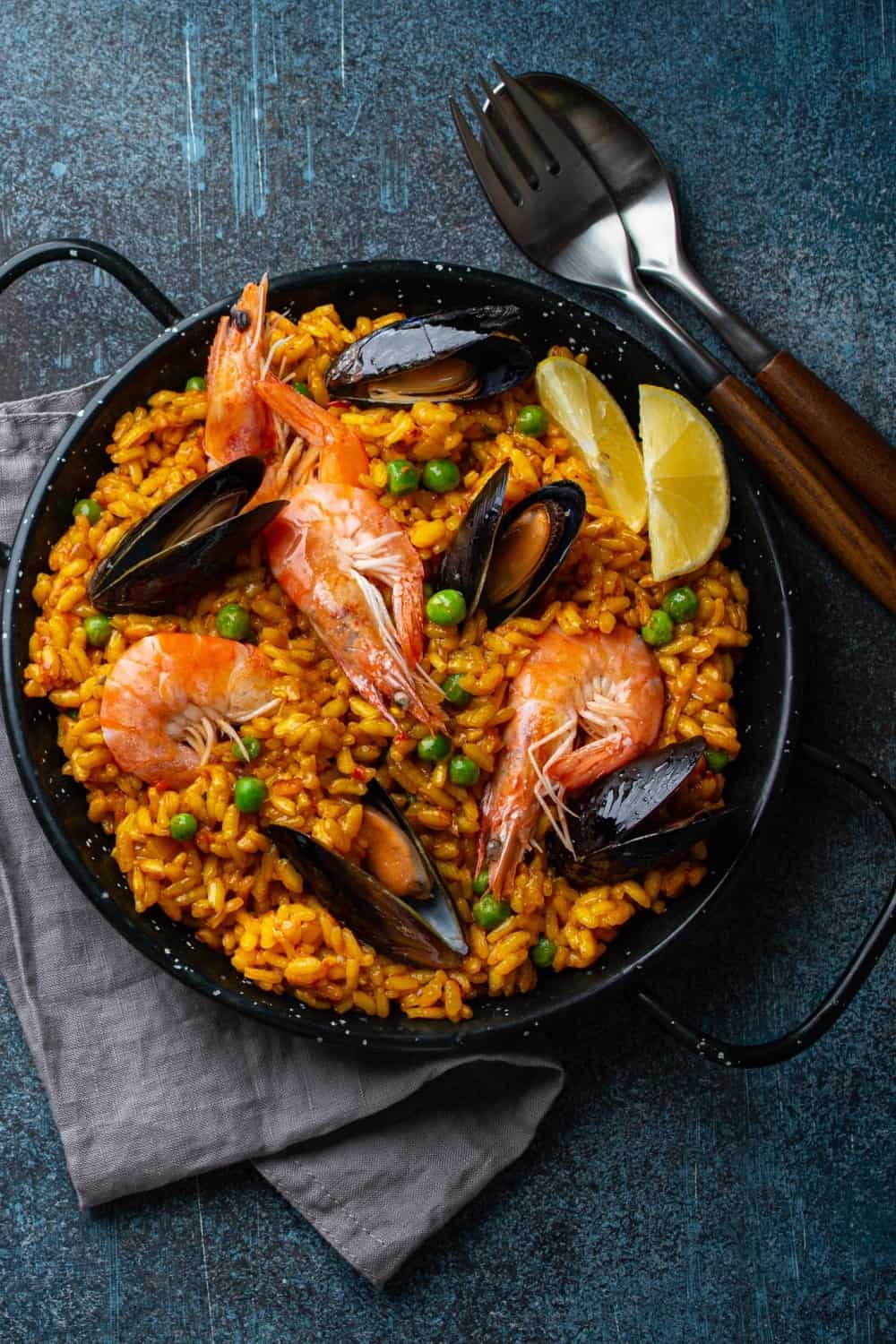 Plato clásico de España, paella de marisco en sartén tradicional sobre fondo de piedra azul vista superior