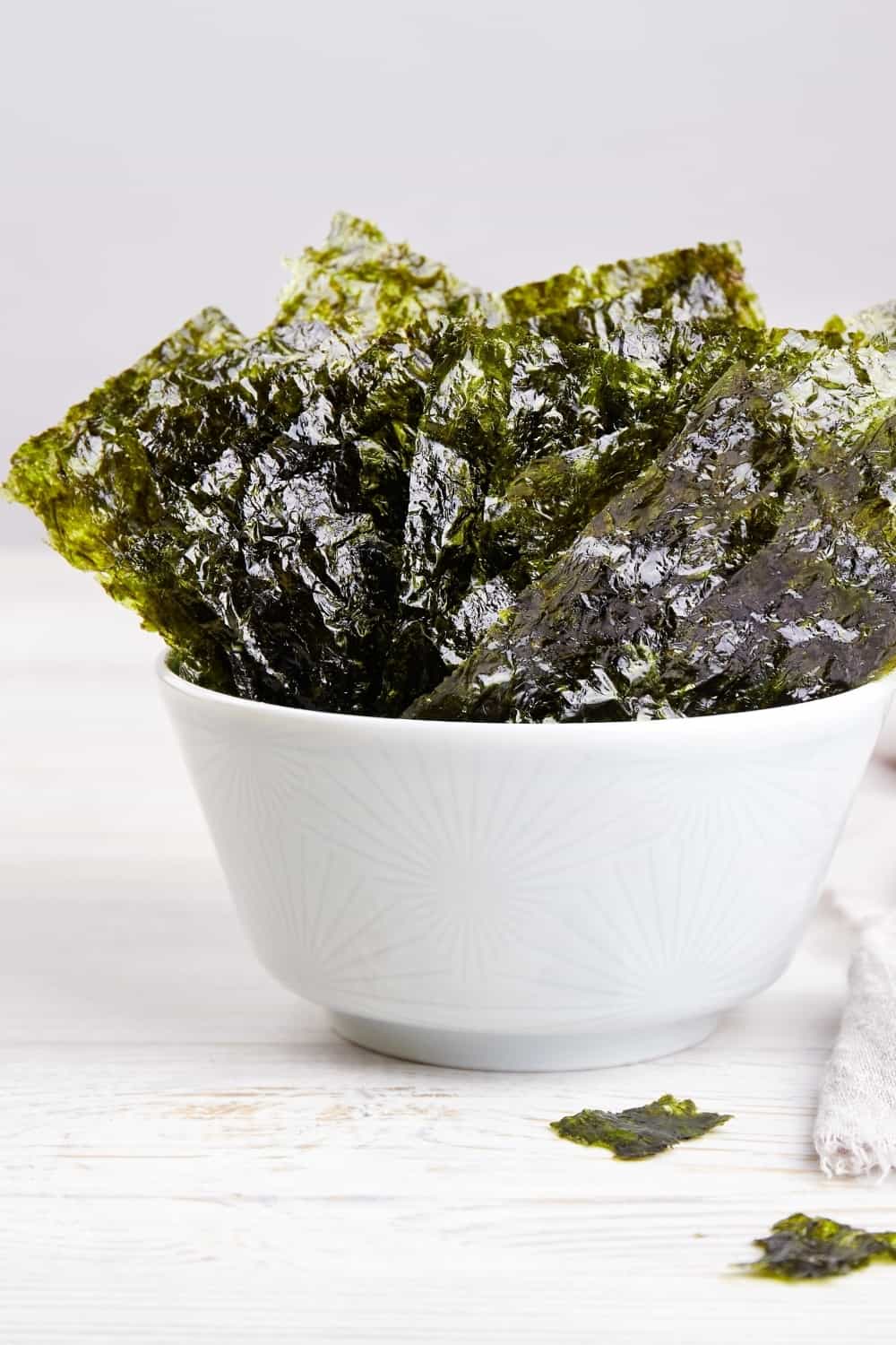 Crispy nori seaweed on bowl on grey background