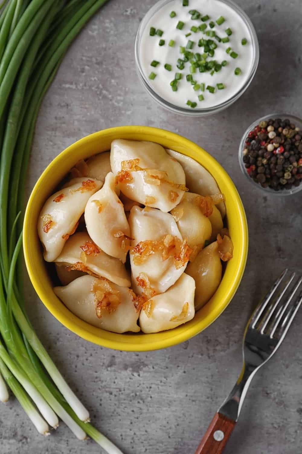 Delicious cooked dumplings with fried onion on grey table