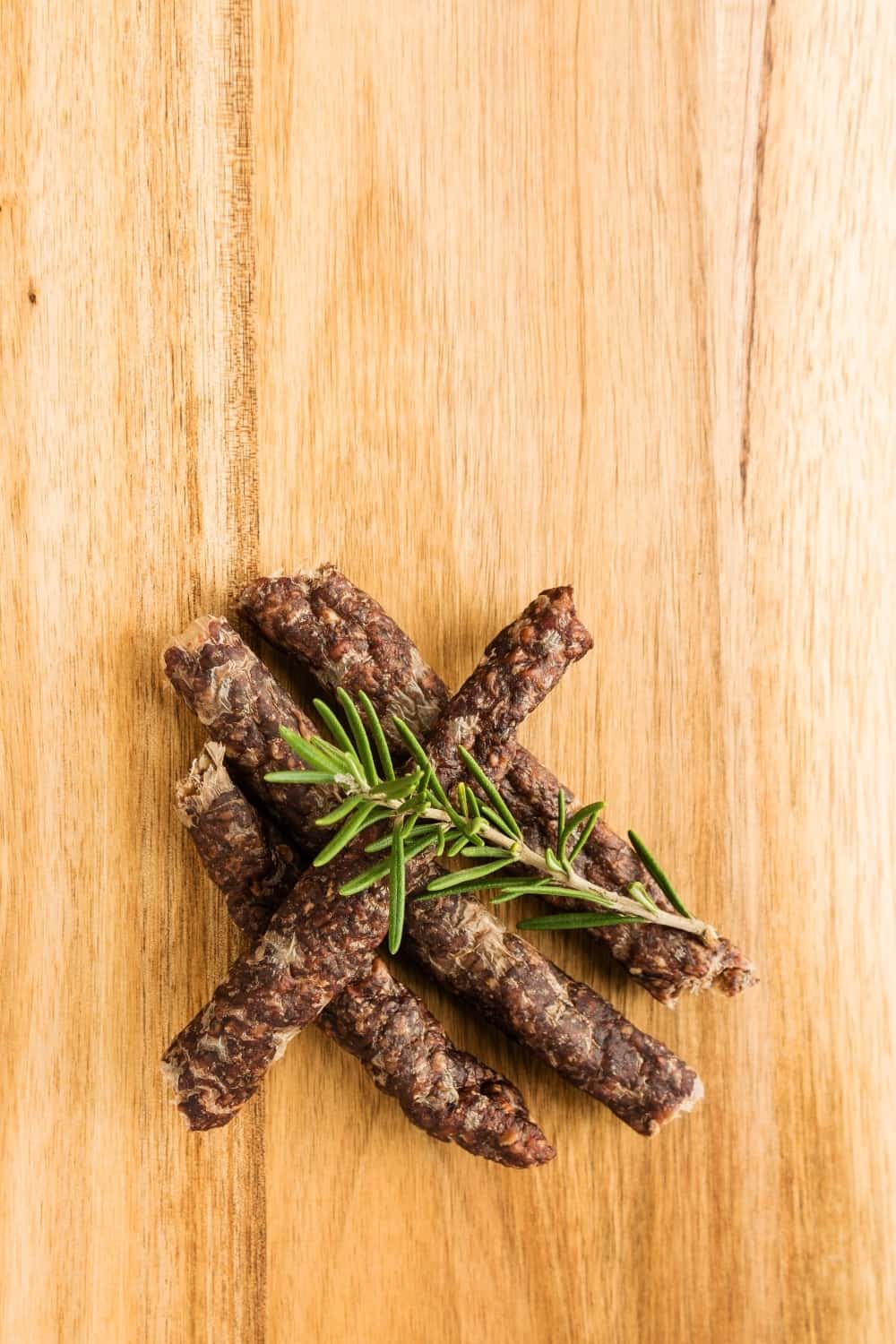 Droewors (biltong) with rosemary on a wooden board,