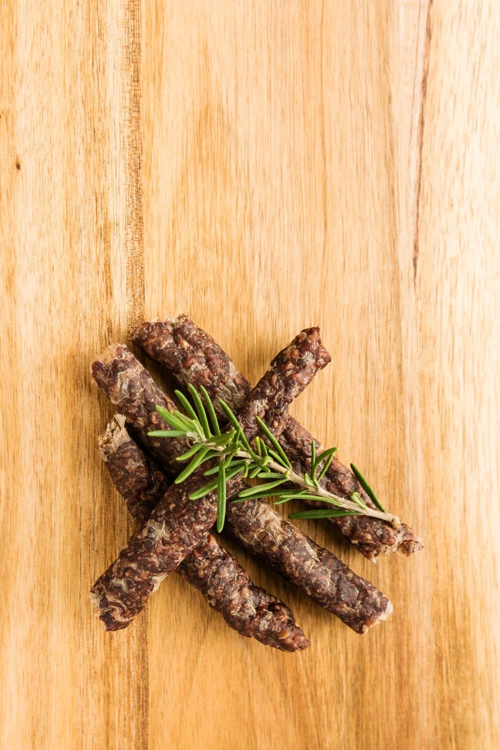 Droewors (biltong) con rosmarino su una tavola di legno,