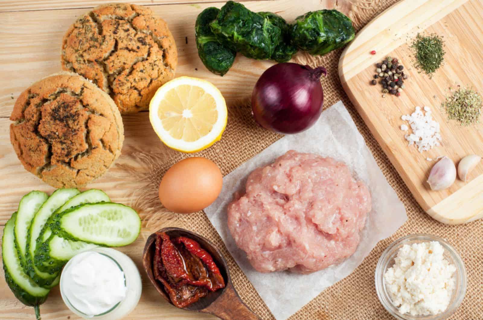 Ground turkey or chicken with ingredients and spices on wooden table