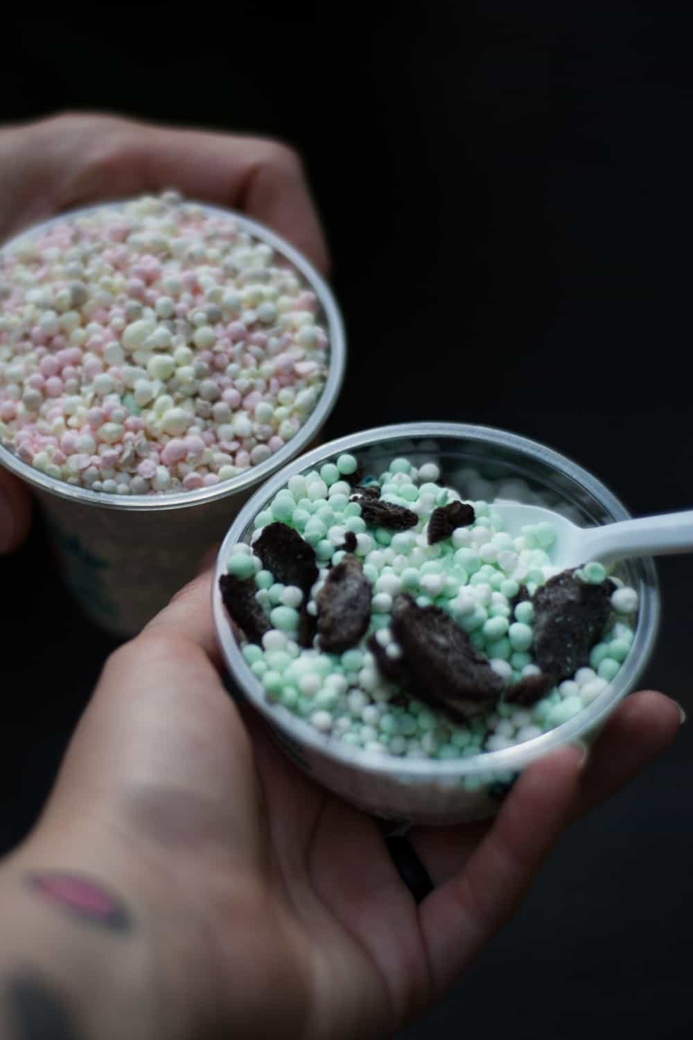 Mãos com tatuagem a segurar um gelado Dippin Dots