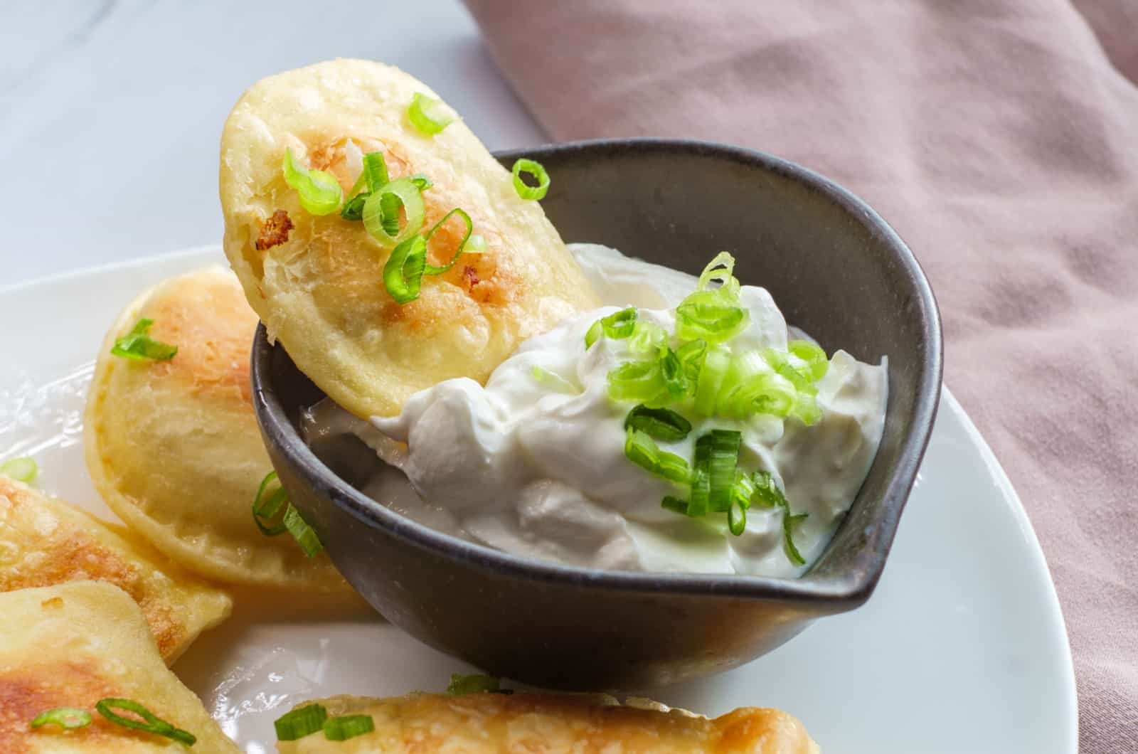 Perogies polacos con cebolla verde picada y crema agria