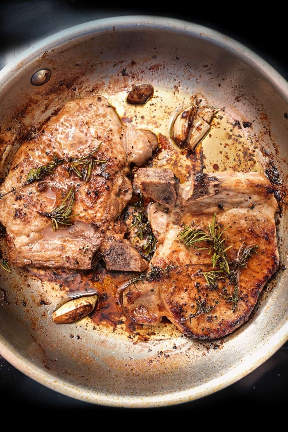 Roasted pork chops with herbs, spices and garlic in a frying pan