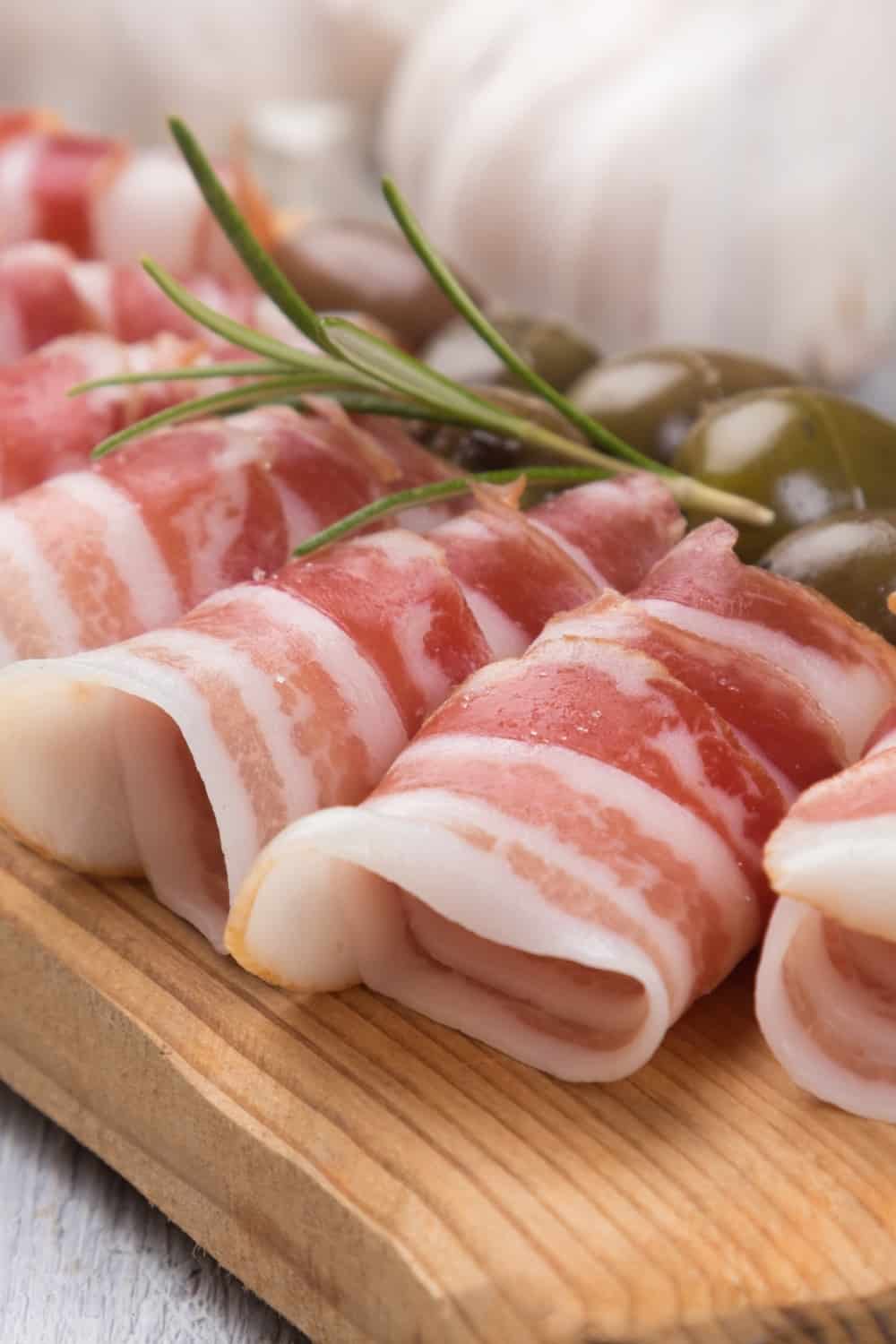 Rolls of pancetta bacon served with pickled olives,