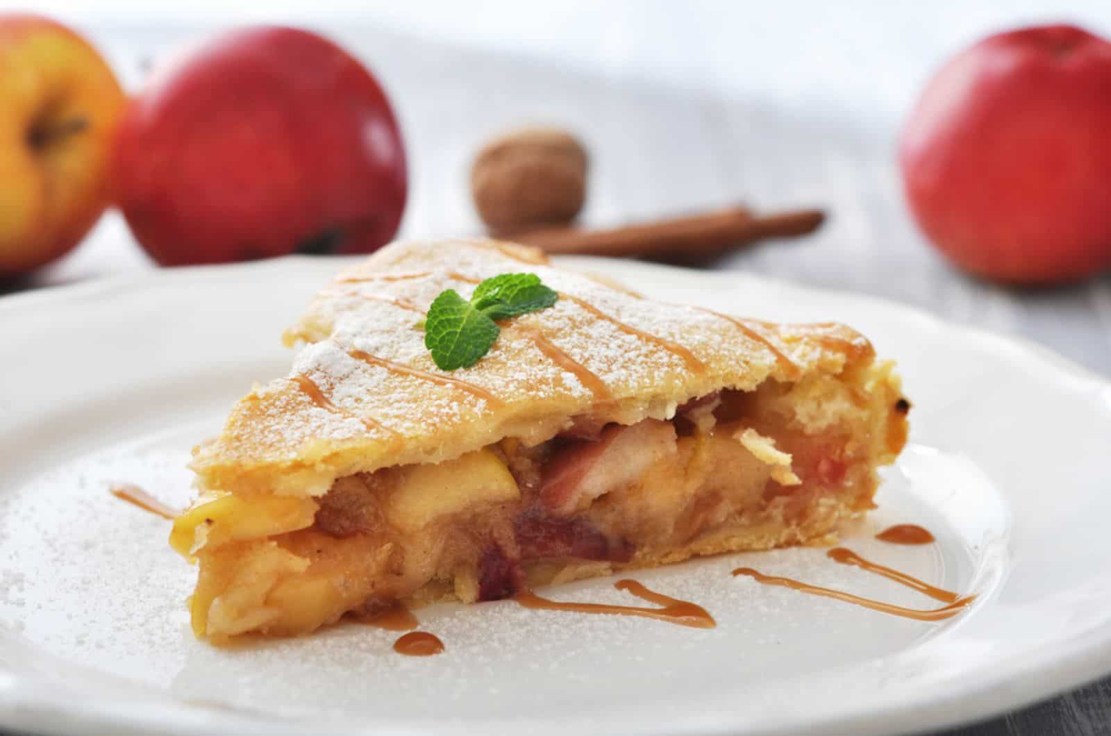 Slice of homemade apple pie with fresh apples