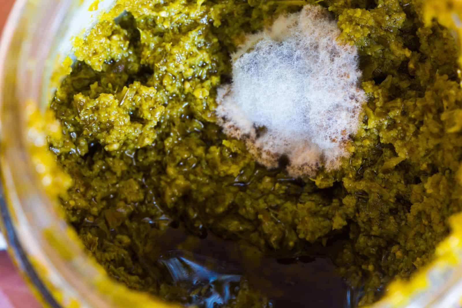 Spoiled pesto paste in a jar and white mold