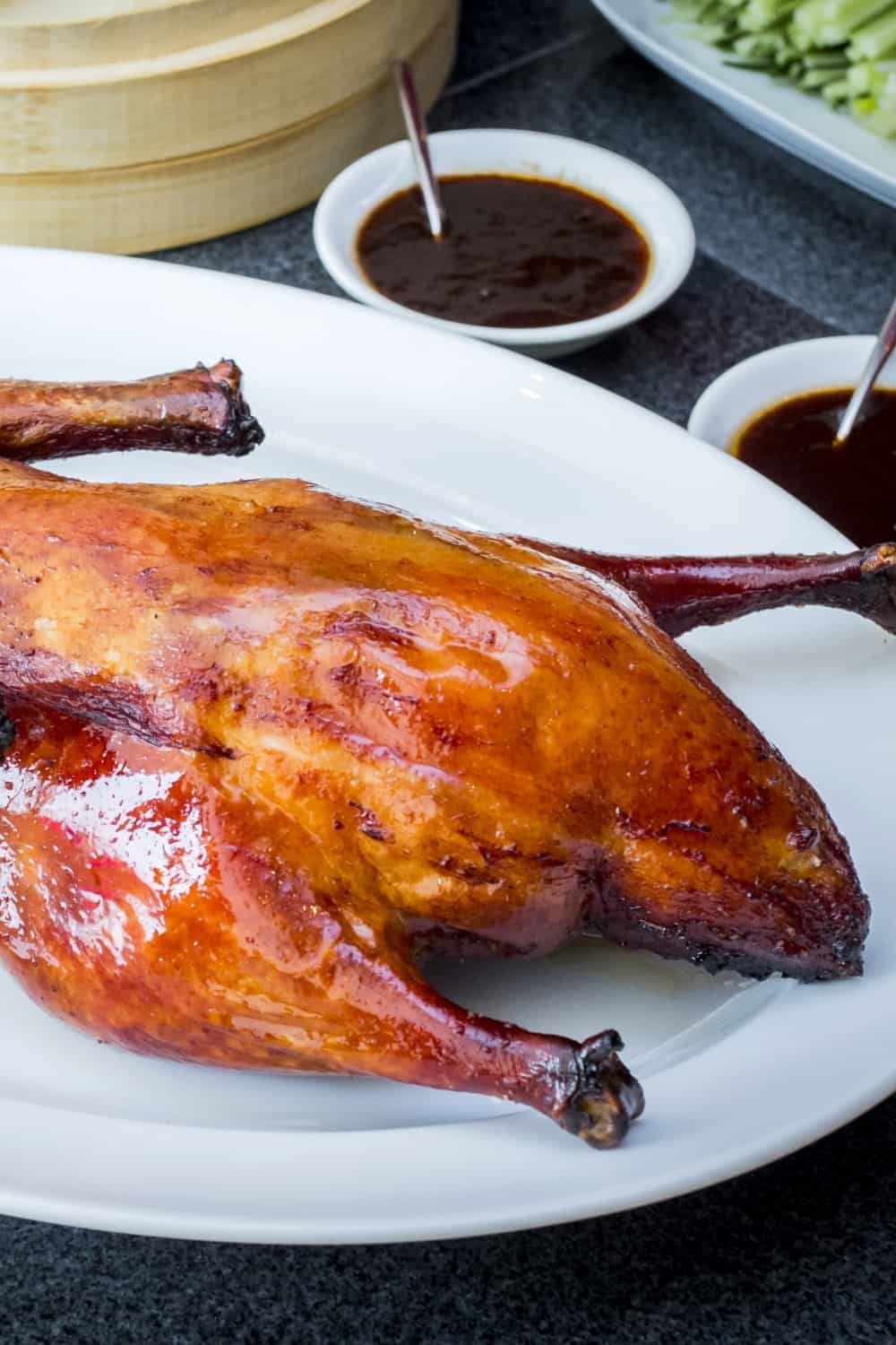 The grilled pecking duck served on the white plate with sauce and vegetable.