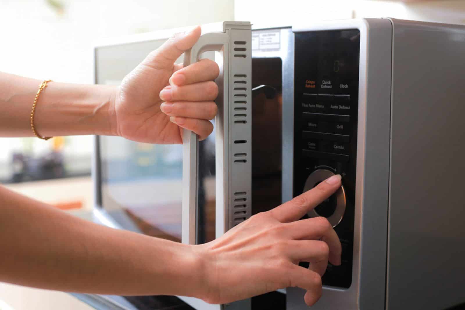 Woman's Hands Closing Microwave Oven Door