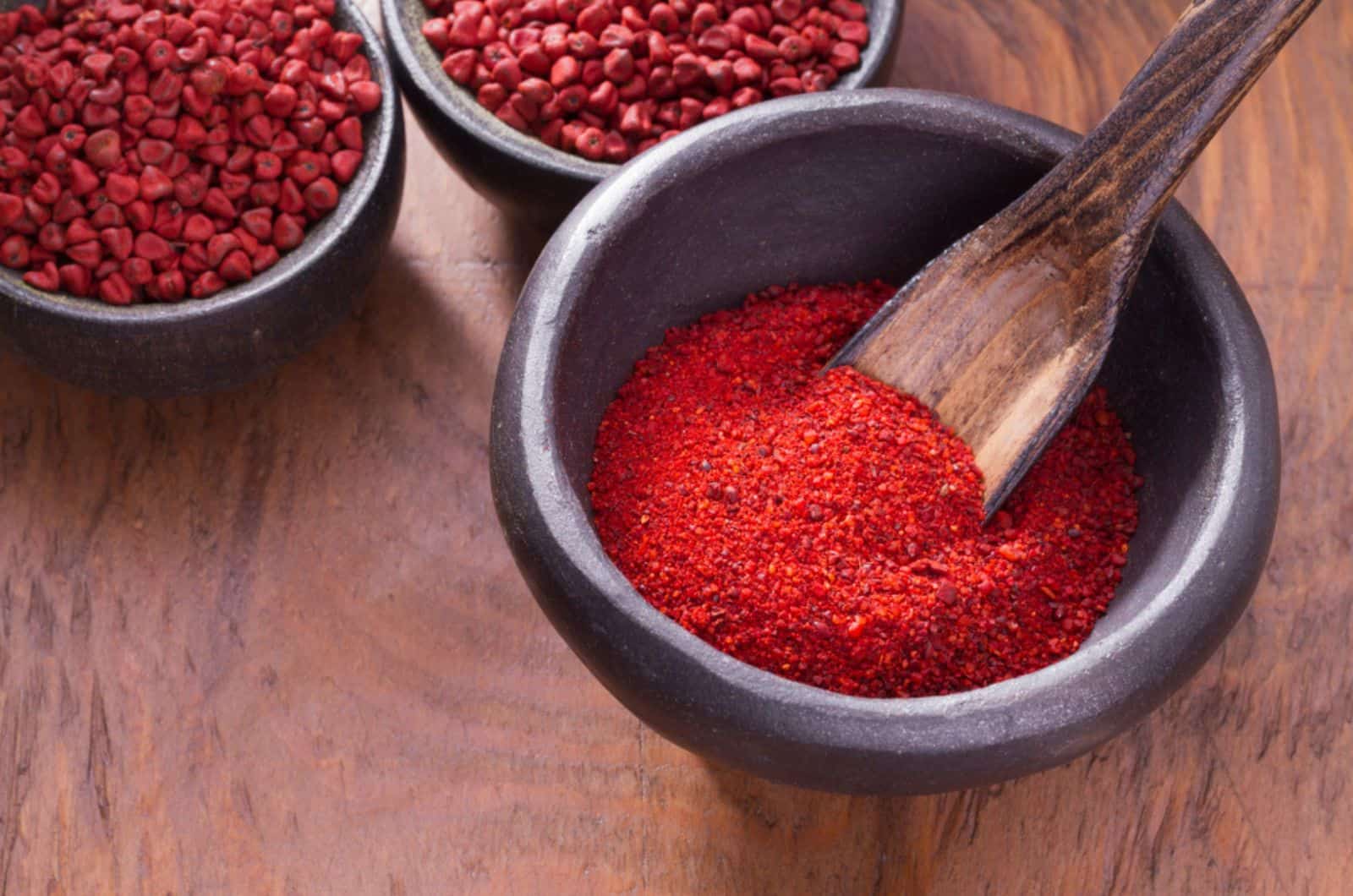 achiote in bowl on wooden background