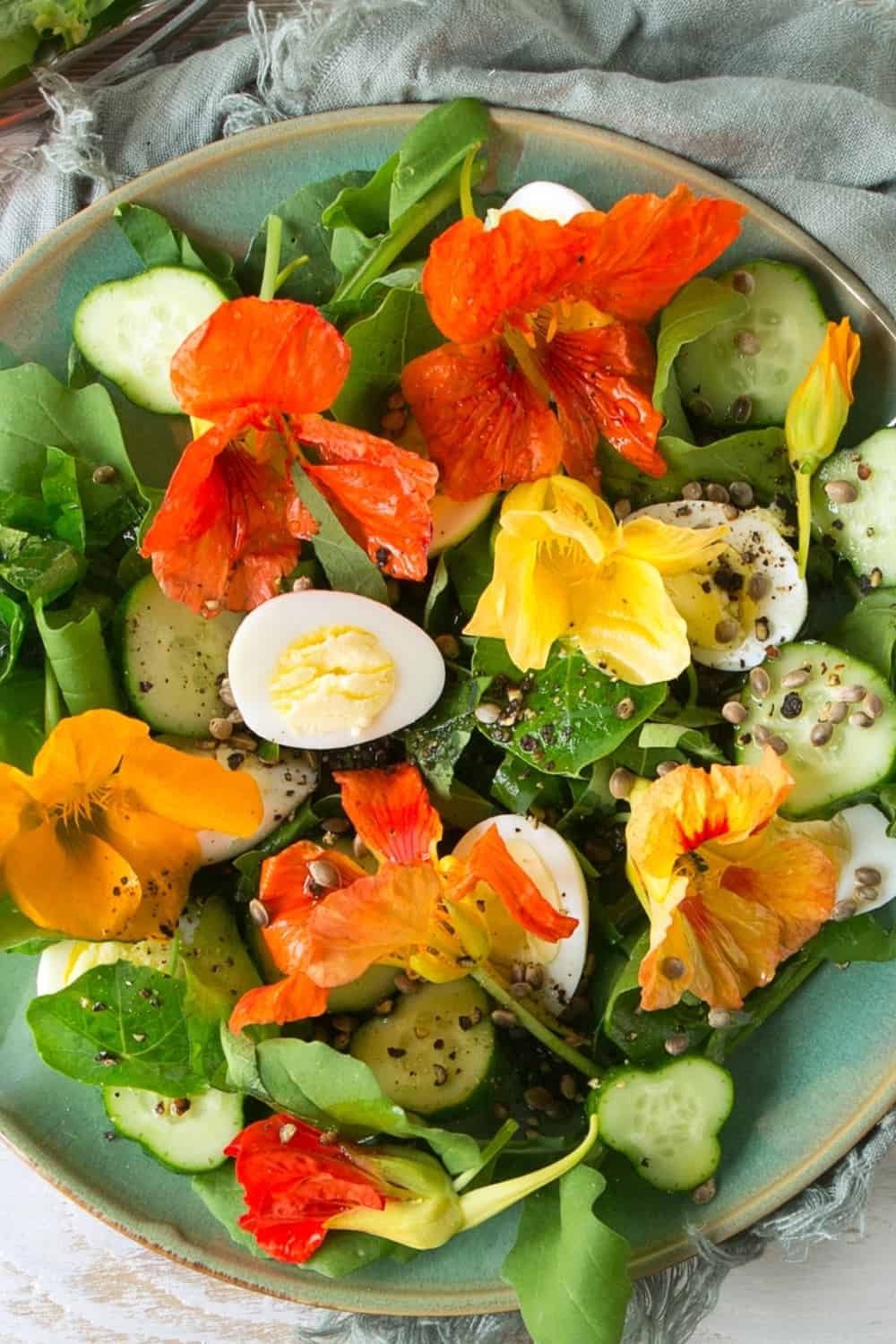flat lay plate of salad with eggs, cucumbers and edible nasturtium flowers