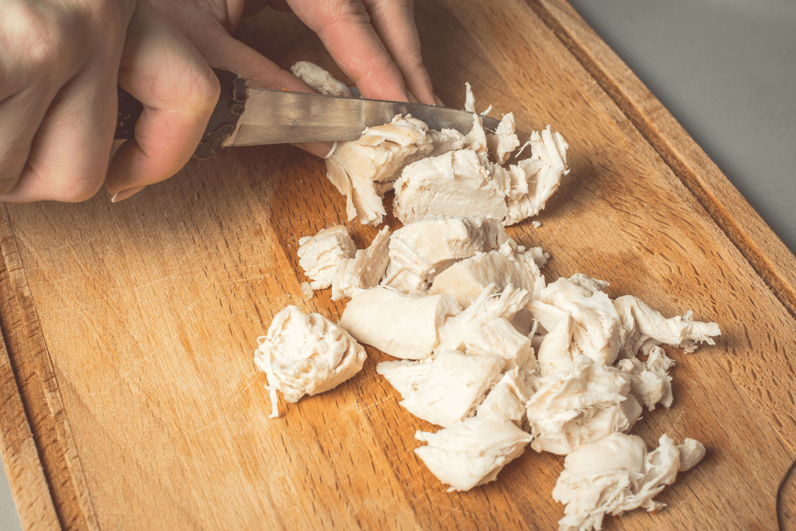 die Frau schneidet das gekochte Huhn auf