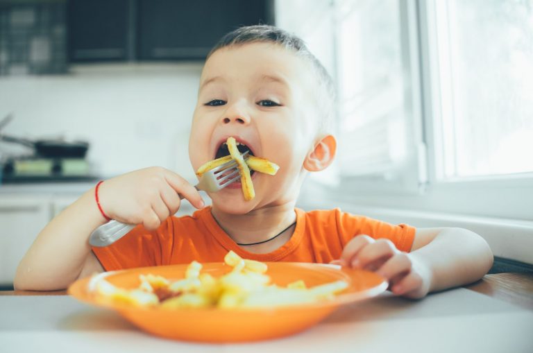 little boy eating french dries