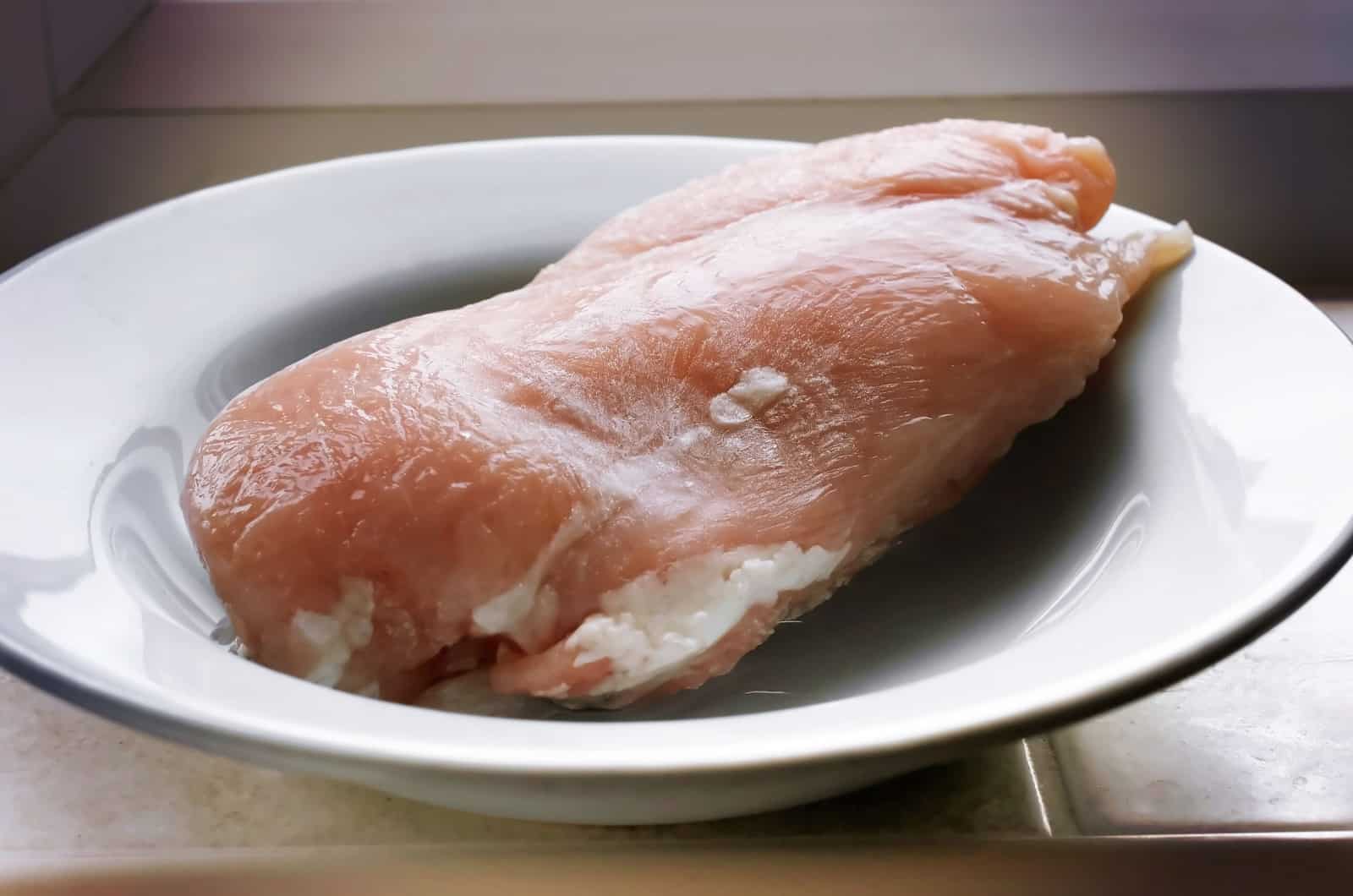 Frozen chicken breasts left to defrost in a bowl
