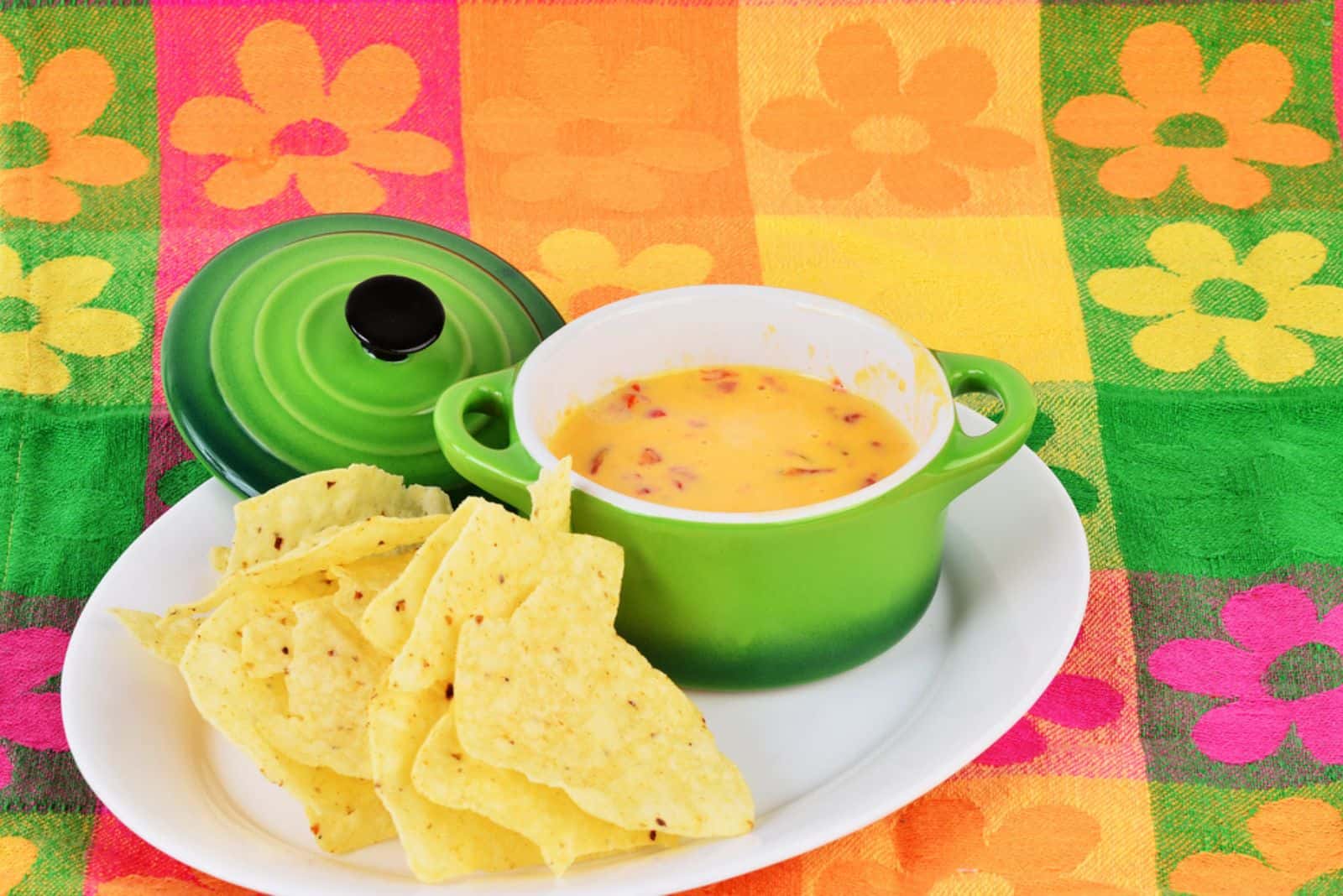 Spicy Chili Con Queso dip in bright green bowl with tortilla chips