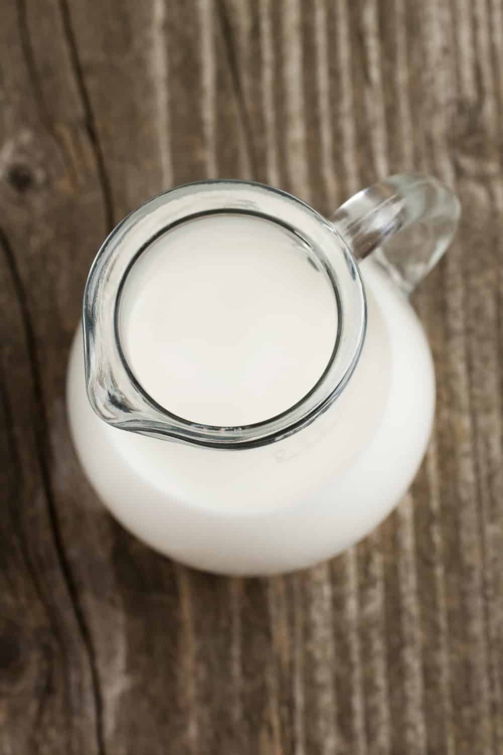 Top view to jug of milk on old wooden table