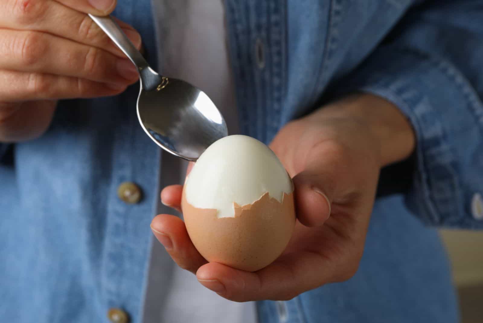 Woman in jean shirt eating boiled egg