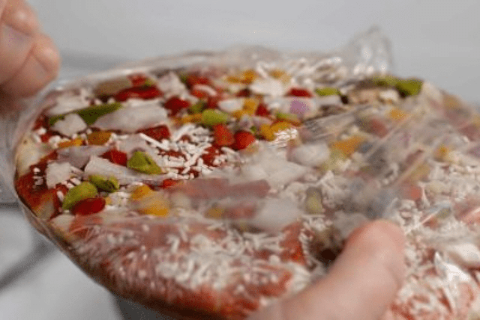a woman unwraps a frozen pizza