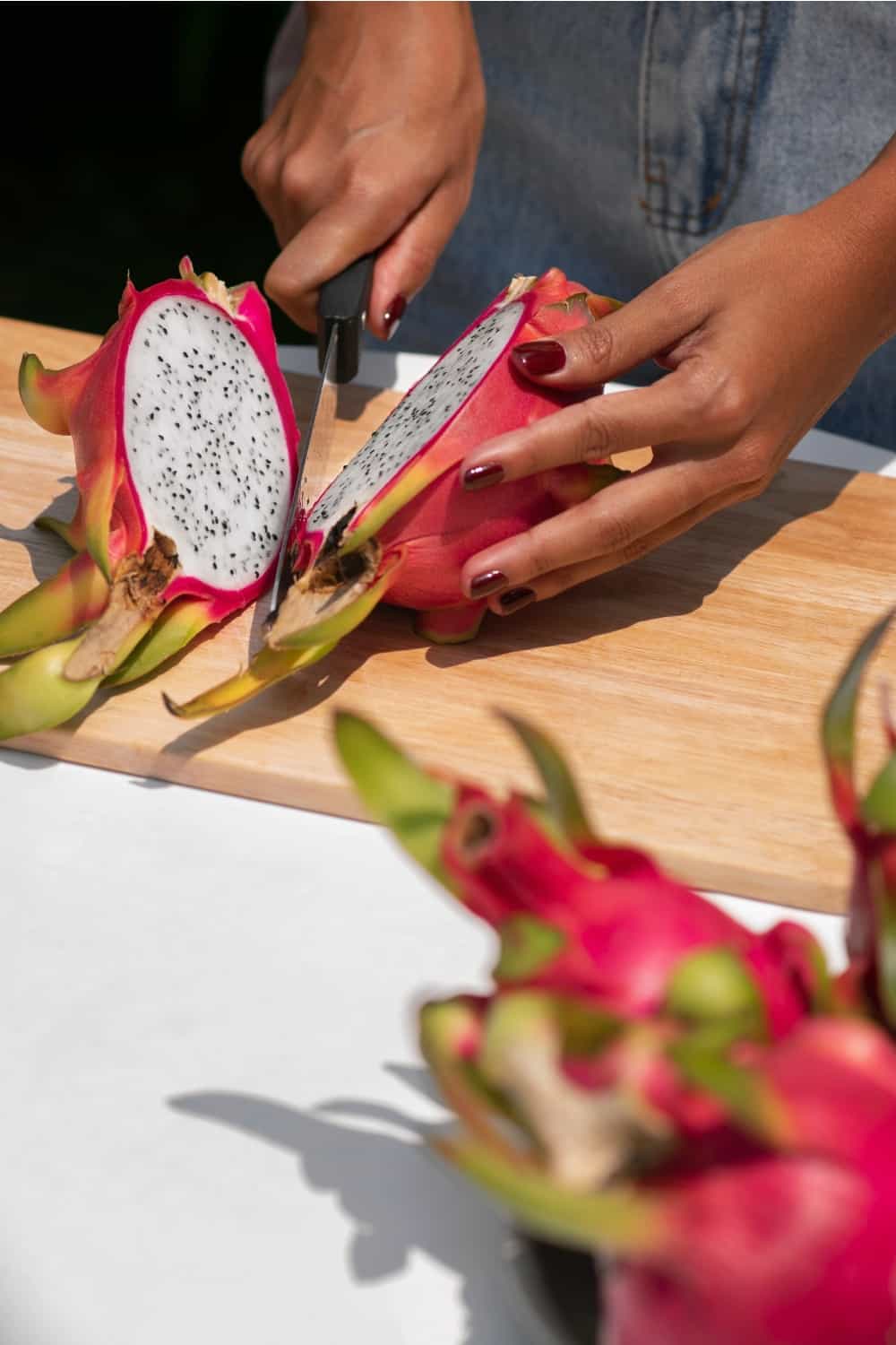 mãos femininas a cortar fruta do dragão