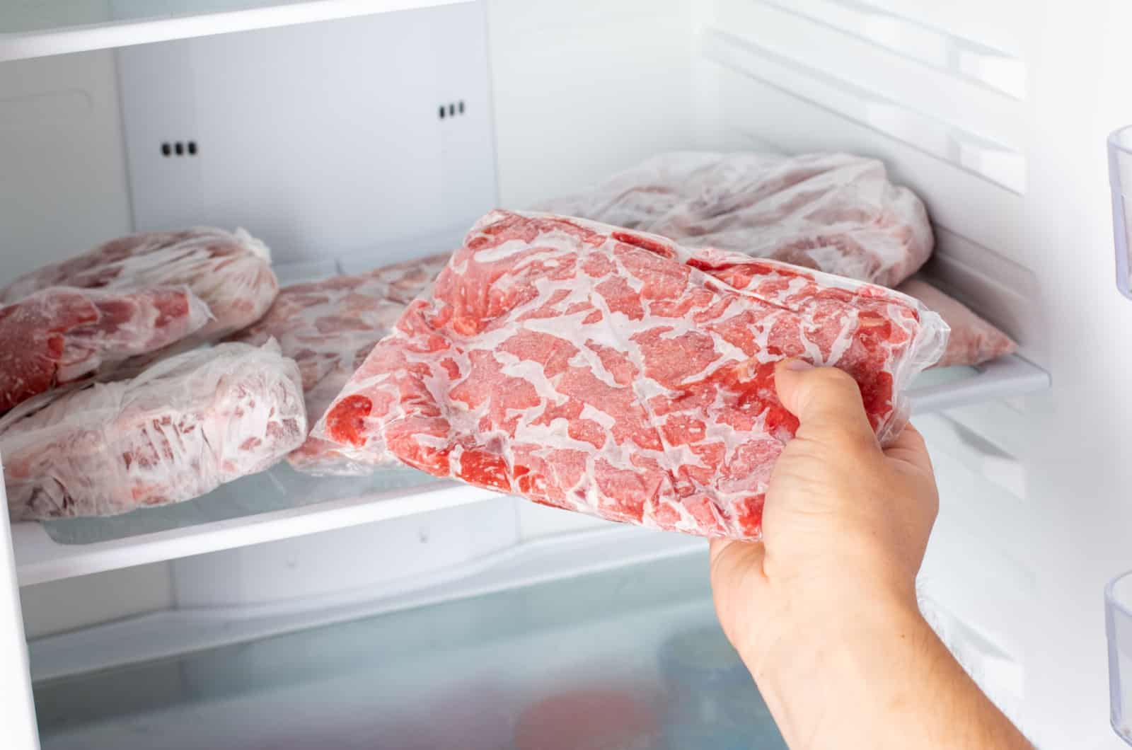 Mann nimmt gefrorenes Fleisch heraus