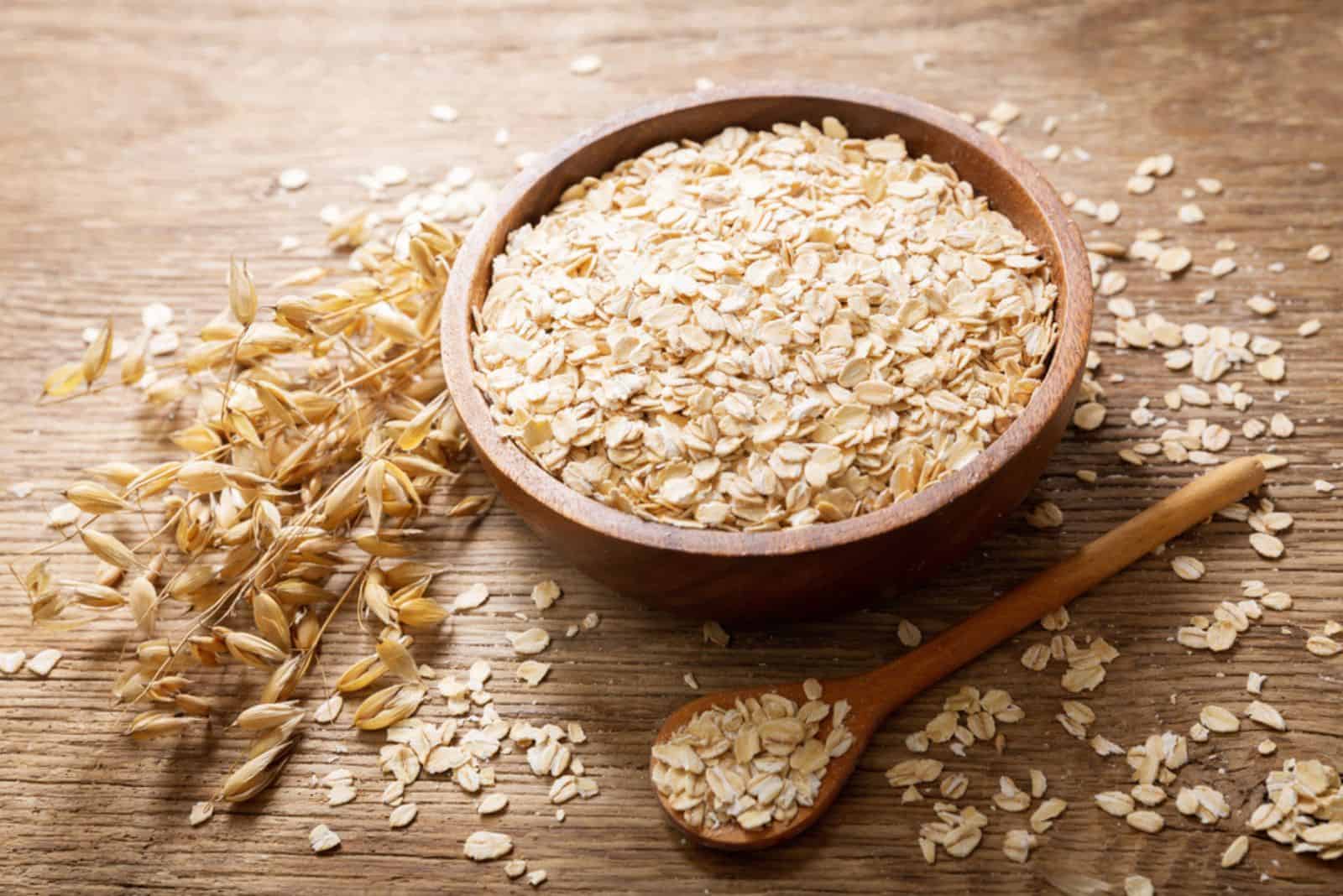 oatmeal flakes and ears of oat on wooden table