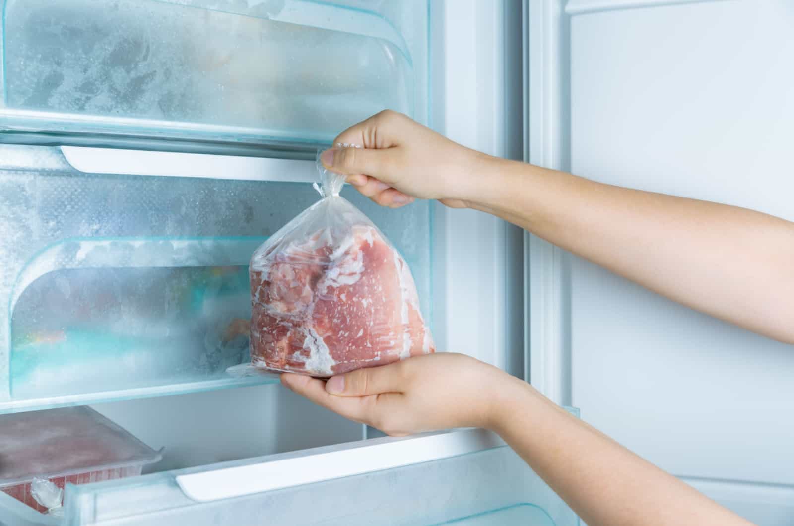 Person, die Fleisch aus dem Gefrierschrank nimmt