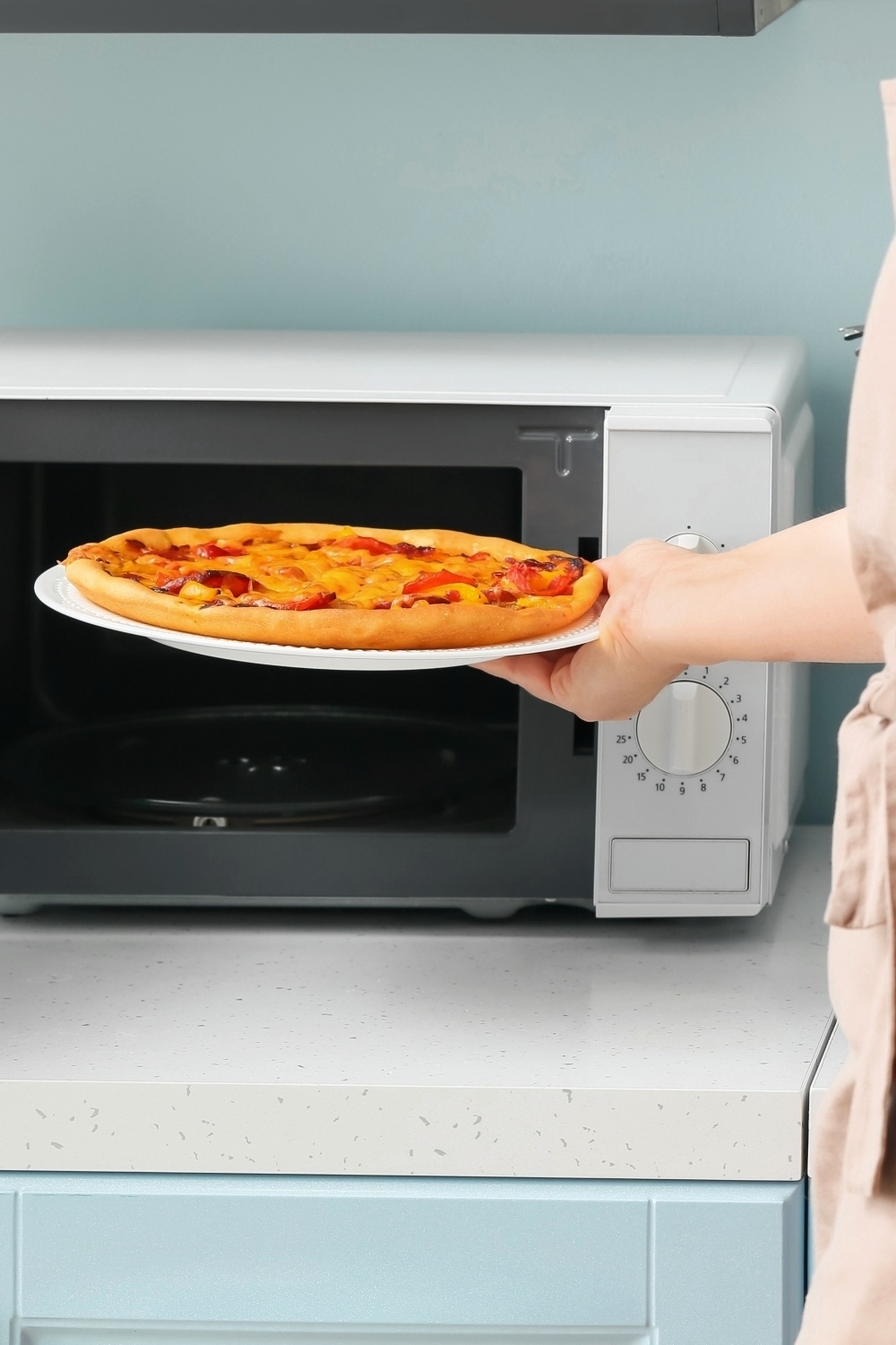 mujer sacando pizza del microondas