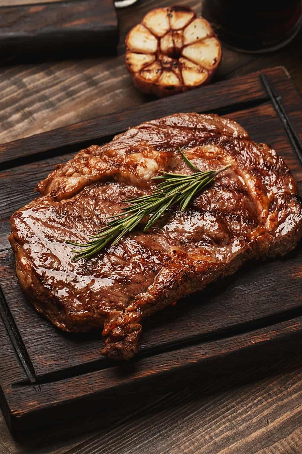 Grilled ribeye beef steak served on wooden board