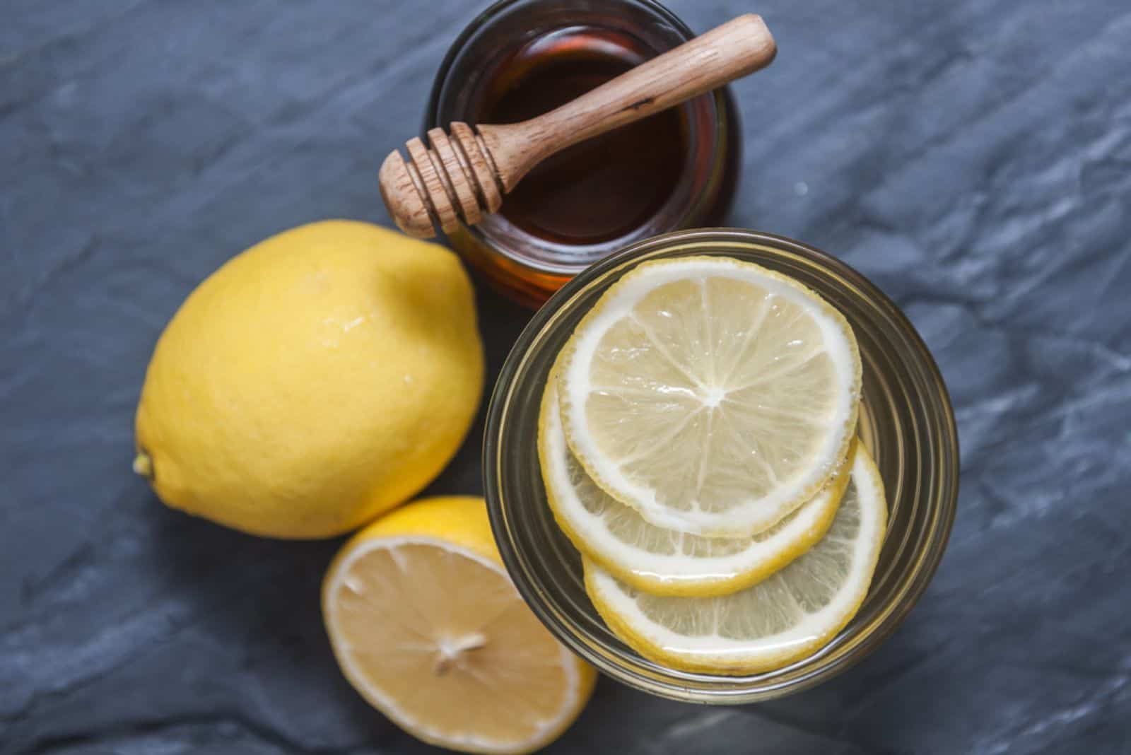 Limonata con limone fresco e miele su sfondo nero di pietra