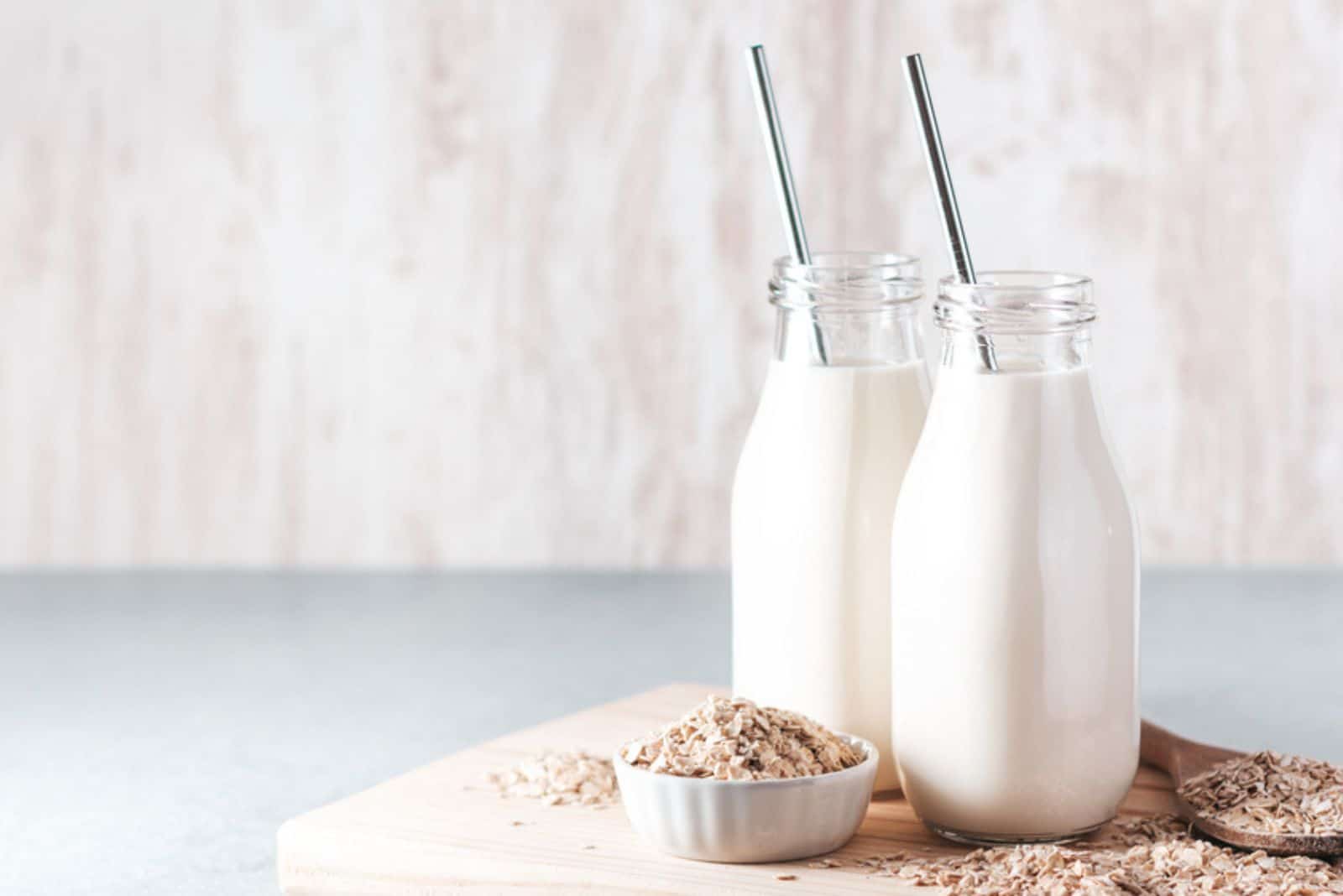 Non dairy oat milk in glass jars with reusable metal straws