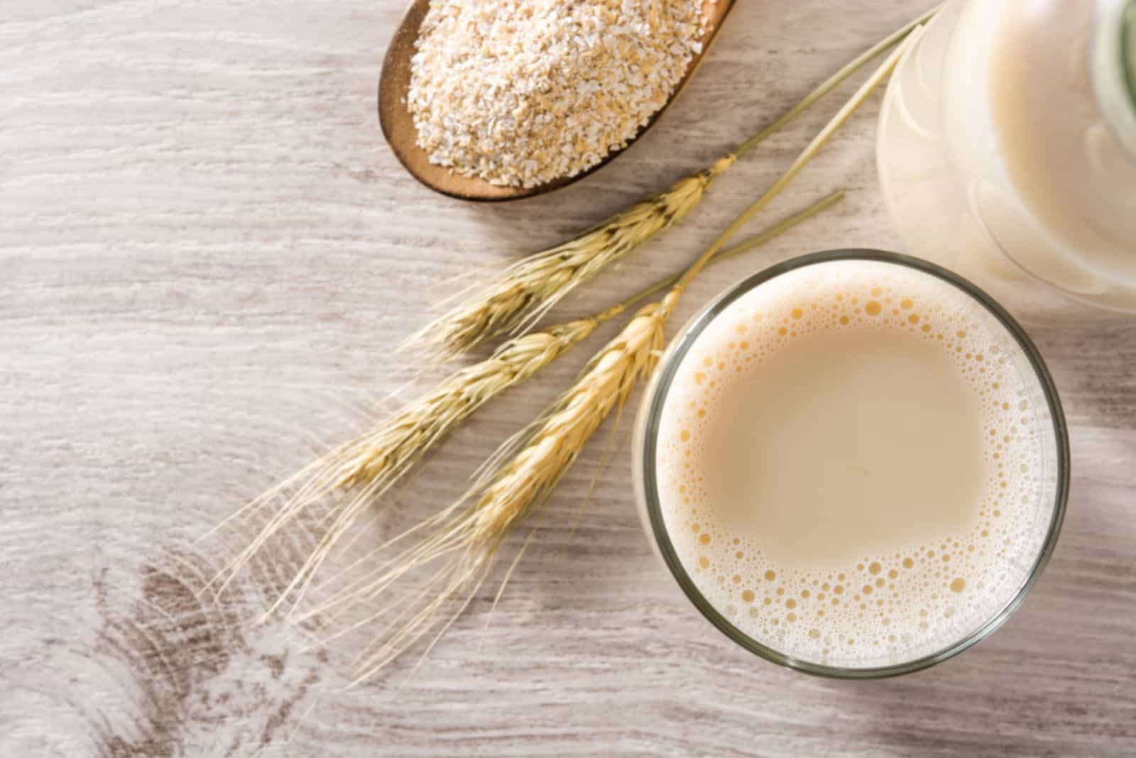 Oats milk in bottle and glass on wooden table