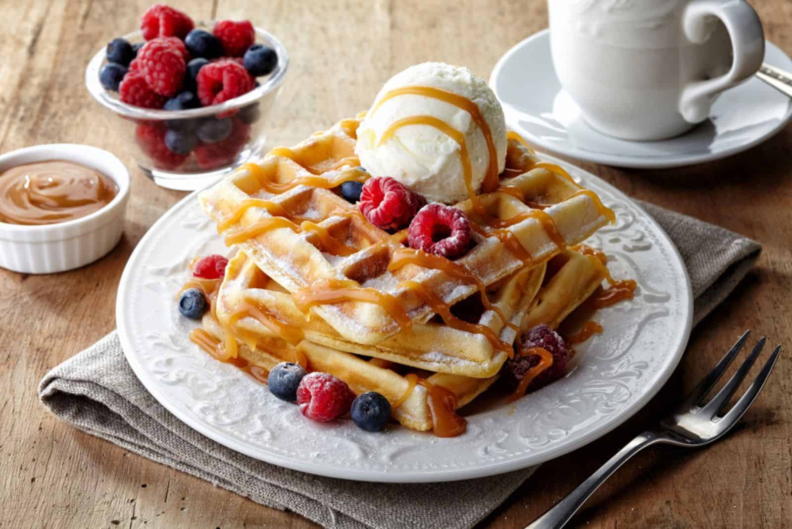 Plate of belgian waffles with ice cream, caramel sauce and fresh berries
