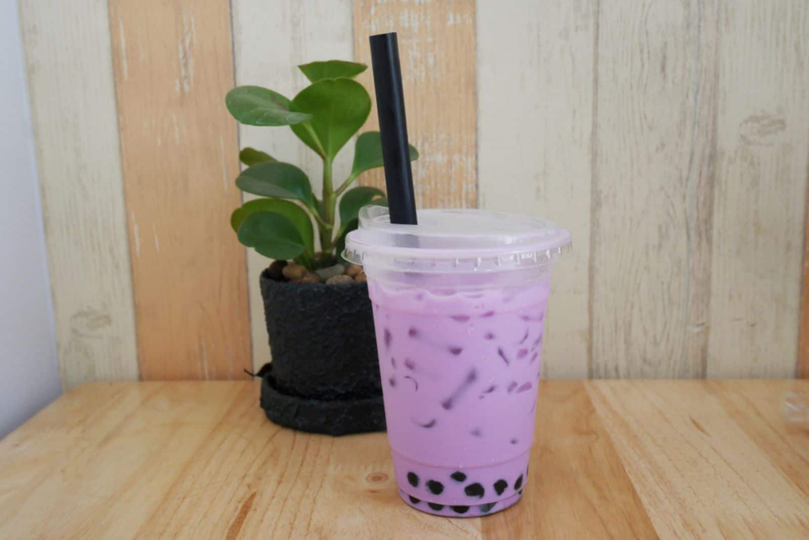 Taro Bubble Milk Tea in Plastic Cup with a Straw on Wooden Table