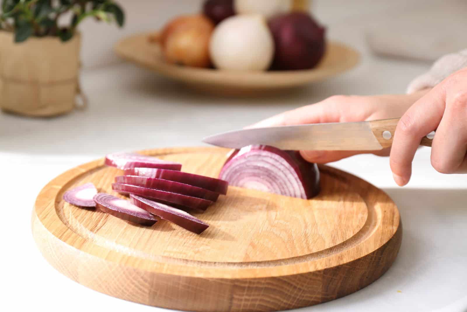 a woman cuts an onion on a cutting board