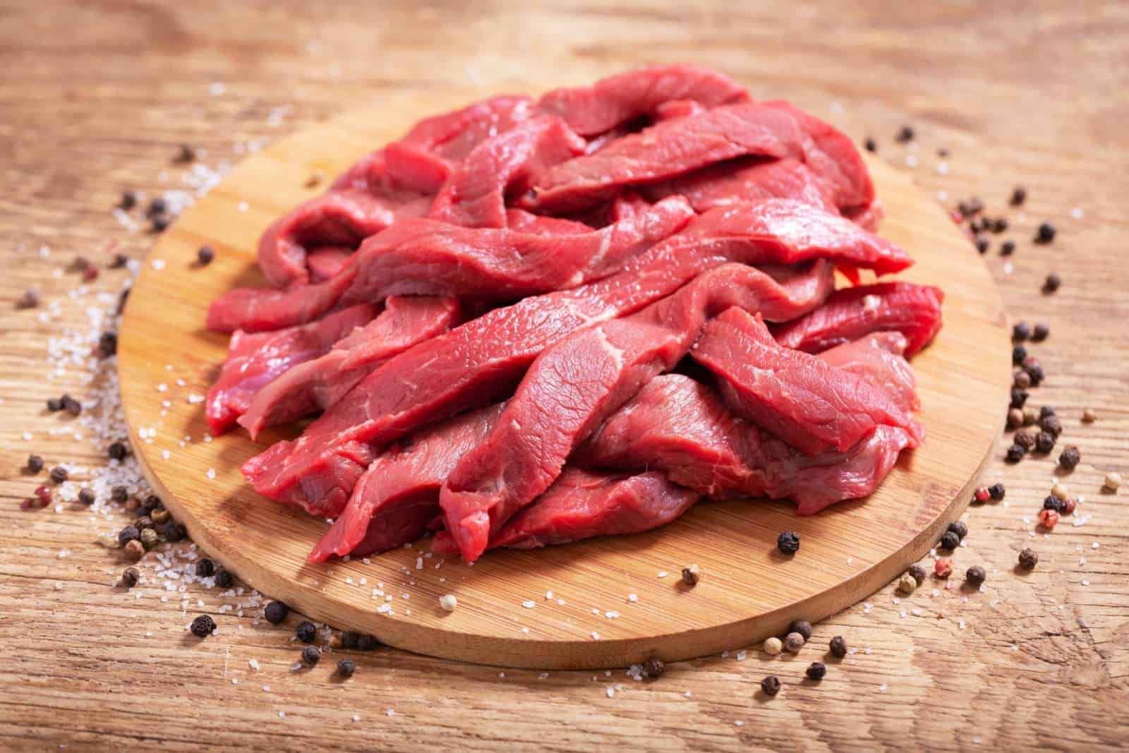 fresh chopped meat with spices on wooden board