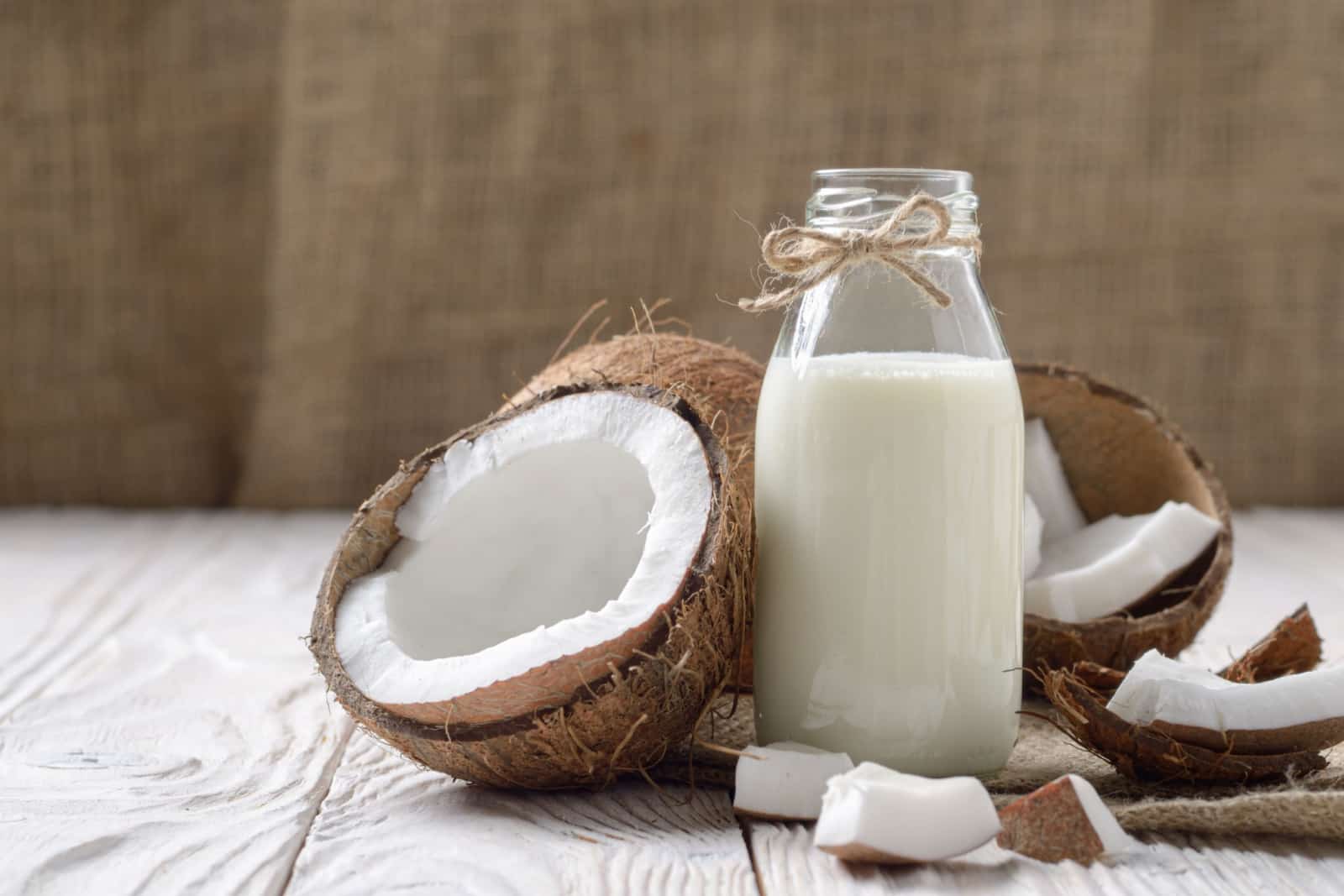 glass jar of coconut milk with coconuts in background