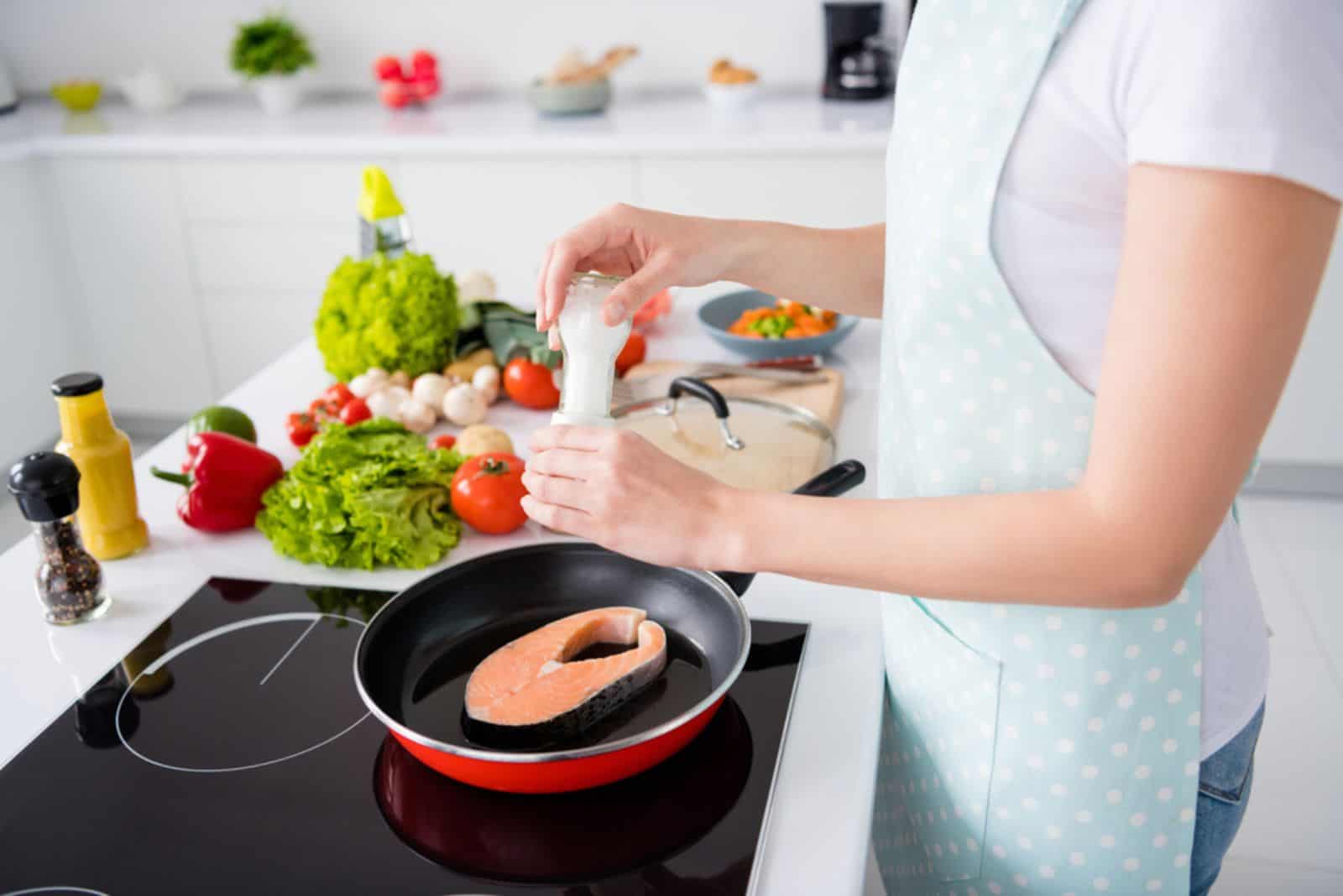 woman cooking salmon fillet
