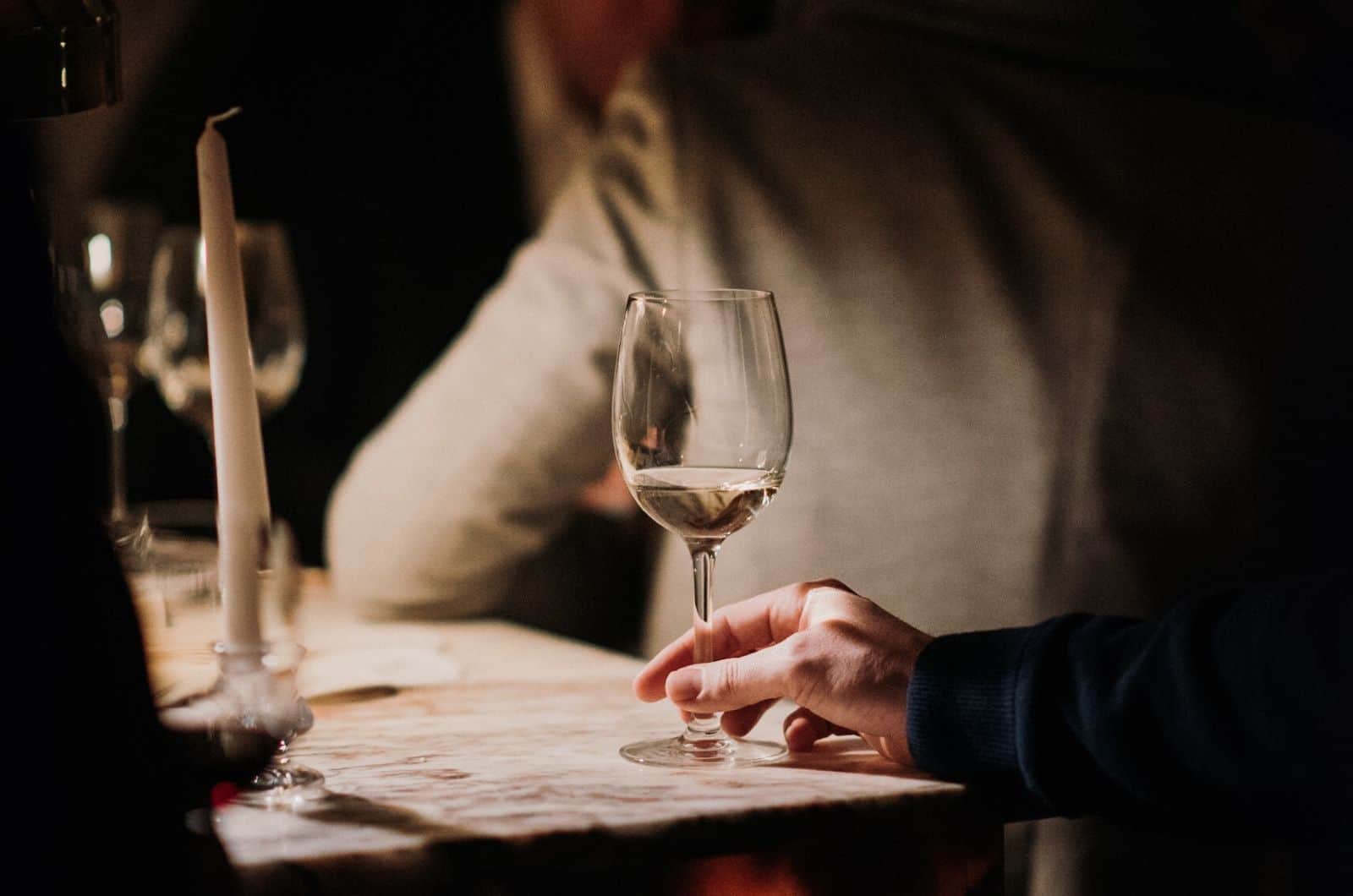 Frau hält ein Glas Wein auf dem Tisch