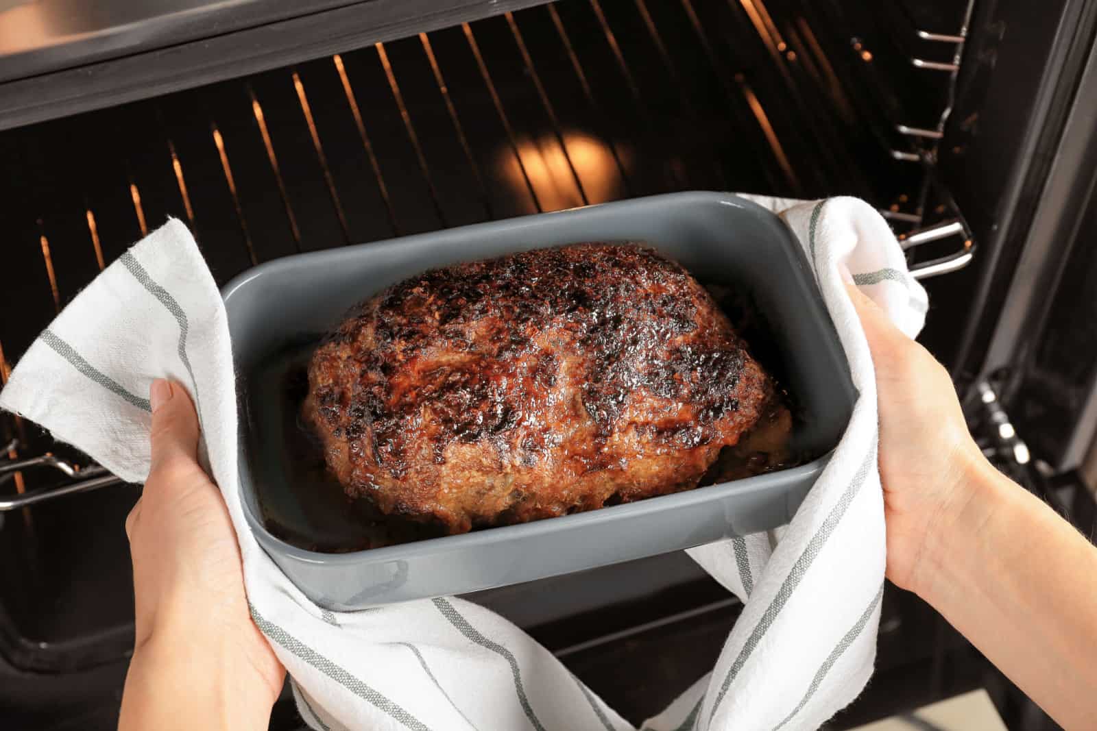 woman taking out meatloaf out of the oven