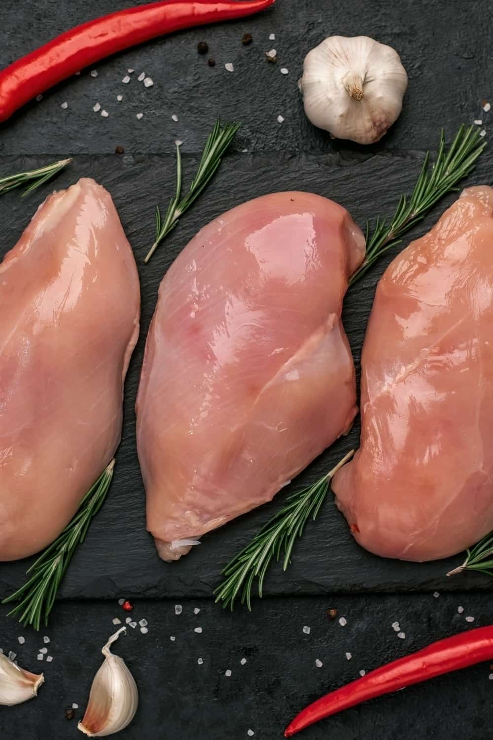 Chicken Breasts and peppers on black board