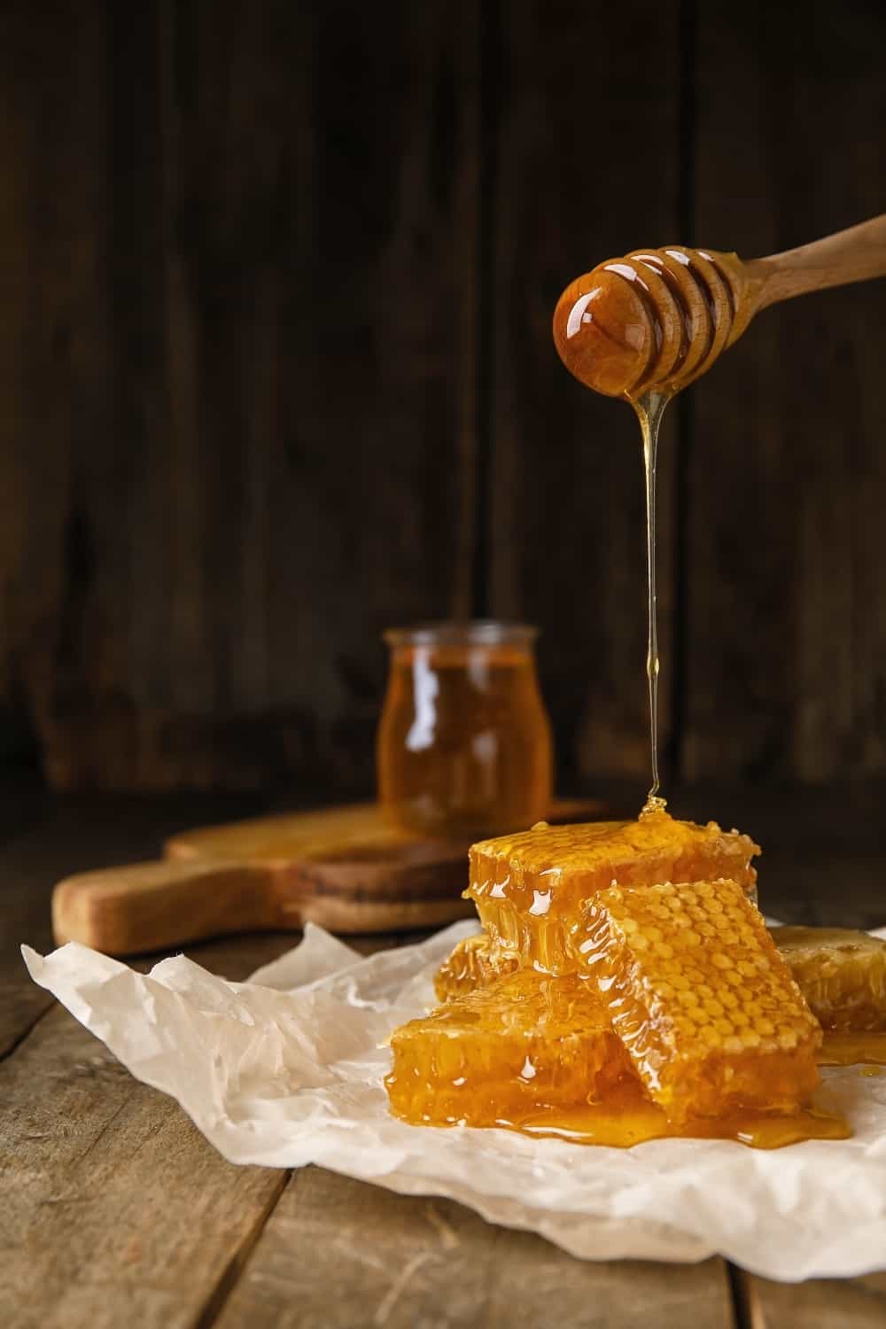 Pouring honey onto combs on wooden background